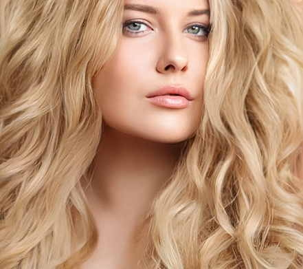 Attractive woman blonde with elegant hairstyle. Example of long,dense and curly hair.