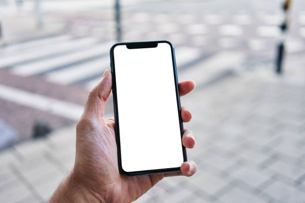 istock Man holding smartphone showing white blank screen at street 1437862688
