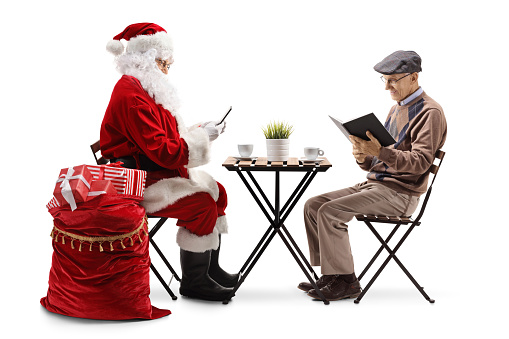 Santa Claus using smartphone and an elderly man sitting at a table and reading book isolated on white background