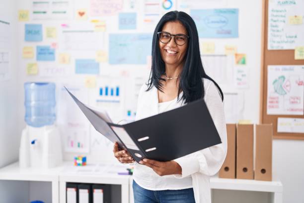 istock Middle age hispanic woman business worker reading document at office 1437863869