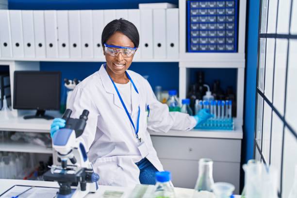istock Young african american woman scientist using microscope working at laboratory 1437864069