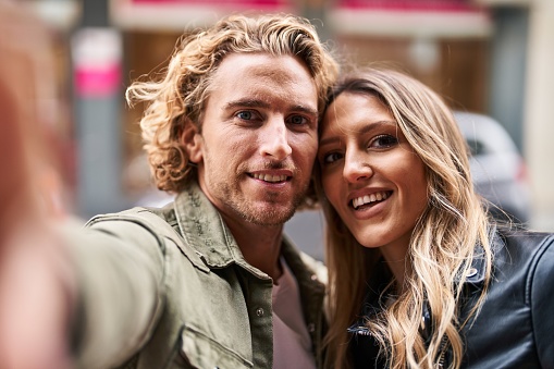 Man and woman couple smiling confident make selfie by the camera at street