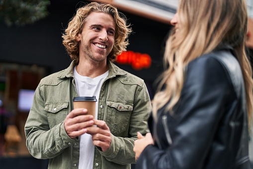 Man and woman couple smiling confident drinking coffee at street