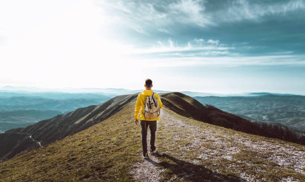 jeune homme avec sac à dos randonnée en montagne - randonneur ayant une journée de trekking par une journée ensoleillée - concept réussi, sportif et inspirant - winter sunset sunrise forest photos et images de collection