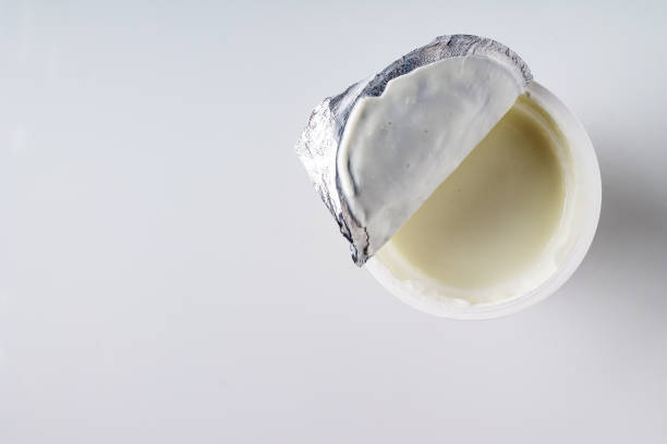 istock open a package with yogurt on a white background, copy space, supermarket product 1437865909