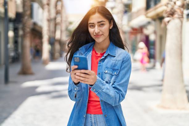 istock Young hispanic girl smiling confident using smartphone at street 1437866276