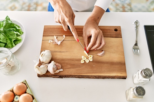 The chef cuts wild garlic on a wooden board with a knife. Chef preparing salad with vegetables, cut vegetables. Healthy and tasty nutrition. Cooking and home recipes. Shallow depth of field