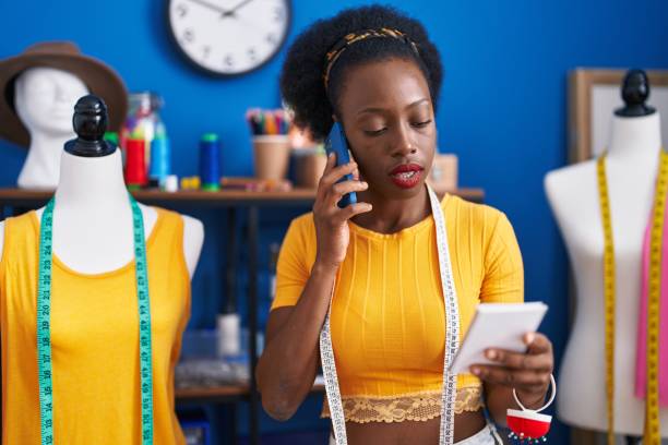 istock African american woman tailor talking on smartphone reading notebook at sewing studio 1437867090