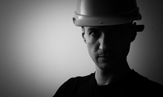 Confident young unshaven business man in light shirt protective construction helmet isolated on grey background. Achievement career wealth business concept. Mock up copy space