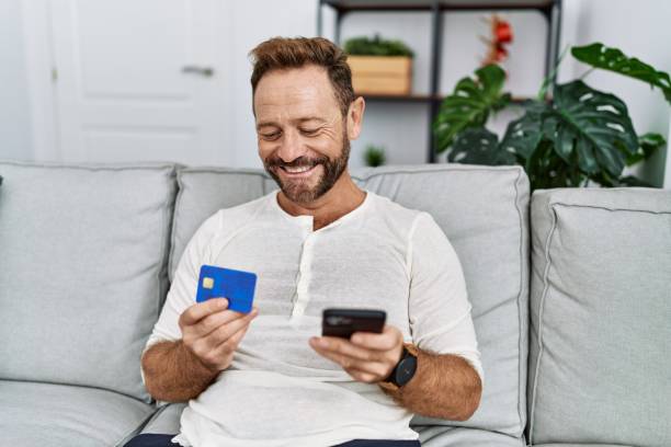 istock Middle age hispanic man using smartphone and credit card at home 1437869017