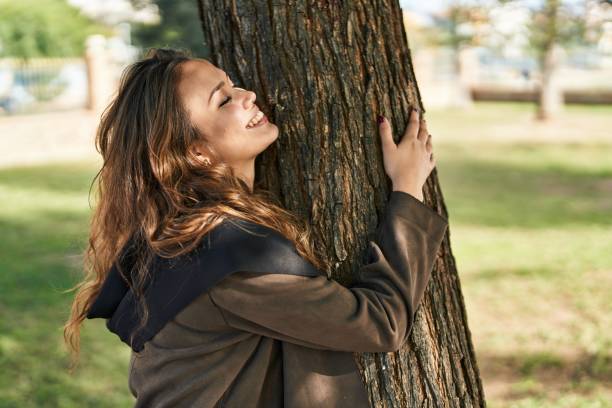 istock Young beautiful hispanic woman smiling confident hugging tree at park 1437869498