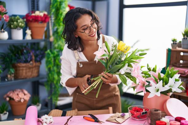 junge schöne hispanische floristin machen blumenstrauß im blumenladen - florist stock-fotos und bilder