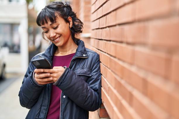 istock Young beautiful hispanic woman smiling confident using smartphone at street 1437870698