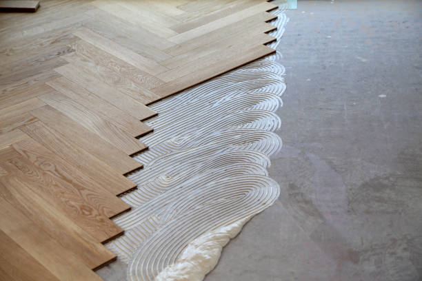 istock Worker laying parquet flooring and installing wooden laminate 1437870915