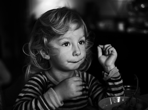 A grayscale shot of a young girl on a dark background