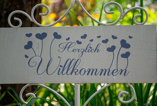 A banner fixed on a garden fence with German text on it
Translation-warm welcome