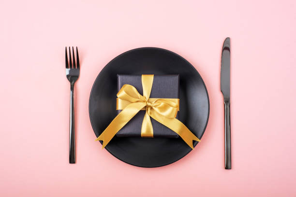 istock Stylish table setting, gift box, black plate, cutlery on pink background. Christmas concept. Top view, flat lay 1437872233