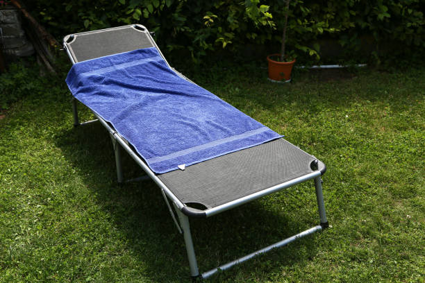 An opened foldable bed with a towel in a garden