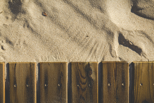 wooden boards of a walkway next to the golden sand of the beach