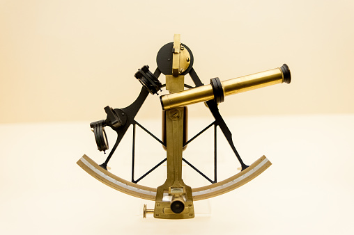A vintage Sextant and Astrolabe isolated on smooth coral background