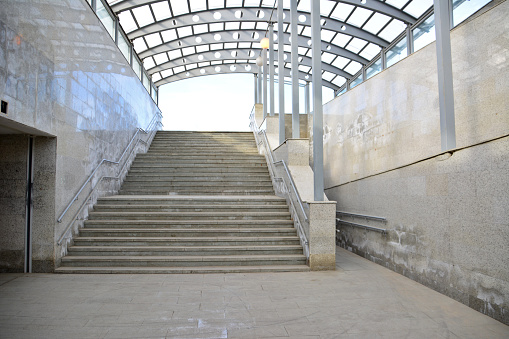 empty concrete subway with glass roof and steps going up