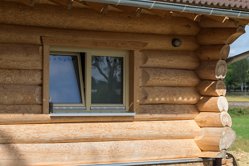 A closeup of a window on a cozy log cabin during daylight