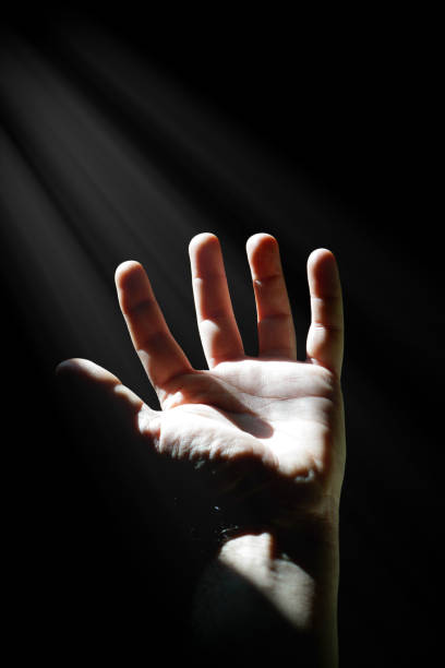 istock man hand up gesturing in the shadows, dark background 1437875184