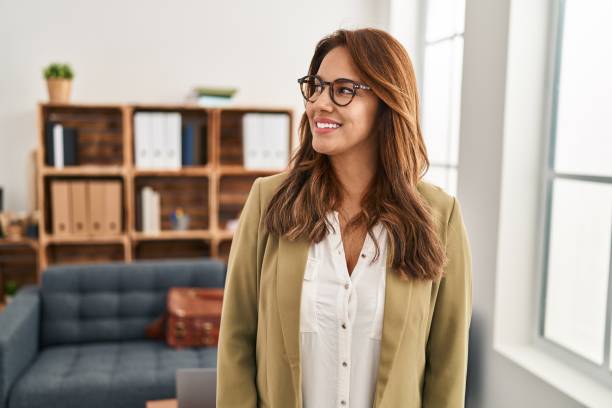 Hispanic woman working at consultation office looking to side, relax profile pose with natural face and confident smile. stock photo