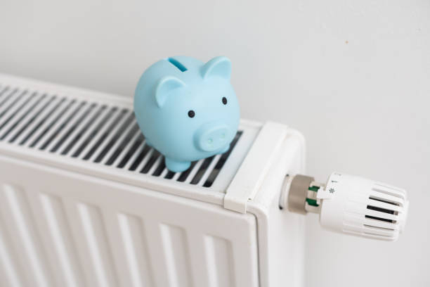 istock Piggy bank on heating radiator against light background. Space for text. 1437875229
