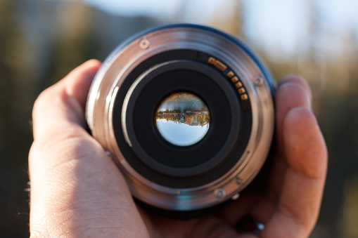 A selective focus shot of a person holding a camera lens