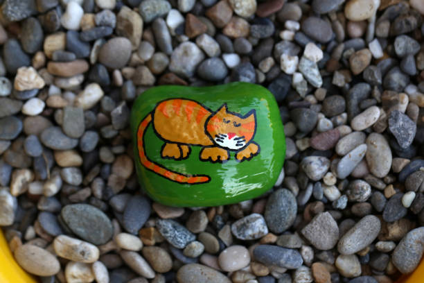 A top view of a painted rock with a cute cat