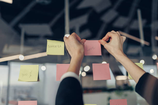 istock Businesswoman hand's is sticking sticky notes on motivation board in office 1437876088