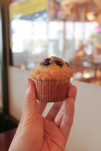 istock Vertical shot of a hand holding a muffin 1437876729