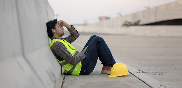 Asian construction workers sit stressed and anxious from working at construction sites.