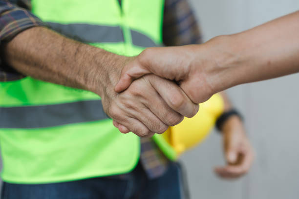 Construction workers shake hands with employers at construction site. stock photo