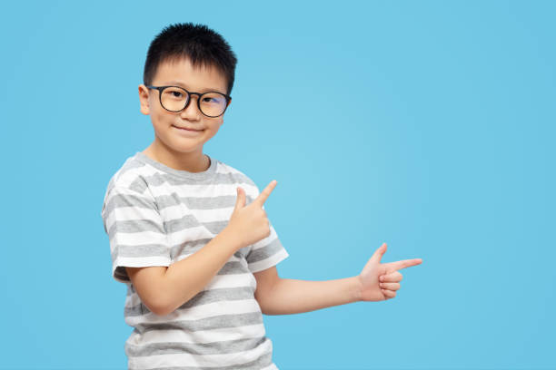 istock Kid with finger pointing and presenting, wearing eyeglasses on blue background 1437879242