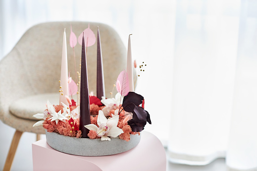 a modern and creative designer advent wreath with candles and flowers in shades of pink, purple and white
