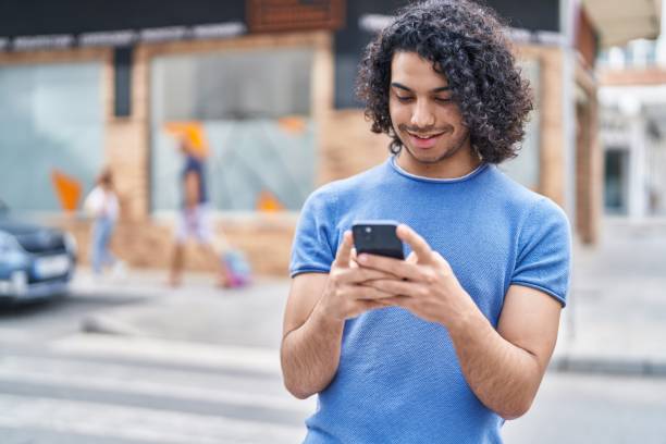 istock Young latin man smiling confident using smartphone at street 1437879802