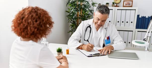 middle age man and woman wearing doctor uniform having medical consultation at clinic - latin american and hispanic ethnicity senior adult mature adult couple imagens e fotografias de stock