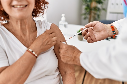 Middle age man and woman wearing doctor uniform vaccinating at clinic