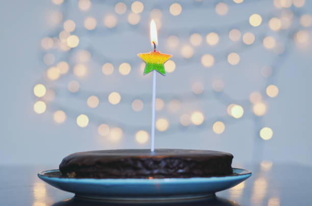 bolo de aniversário festivo com velas e decoração de carnaval colorida contra fundo bokeh brilhante. festa e celebração de feriado - bakery baked biscuit sweet food - fotografias e filmes do acervo