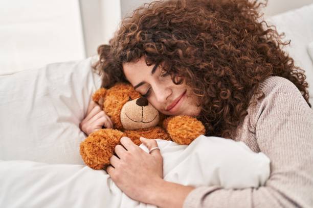 istock Young hispanic woman hugging teddy bear lying on bed sleeping at bedroom 1437882815
