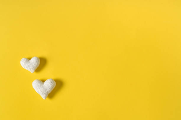 istock Two white knitted hearts on a yellow background. 1437883256