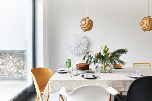 A gingerbread cake stands on a table decorated in a modern, Christmassy way, photographed in high resolution with copy space