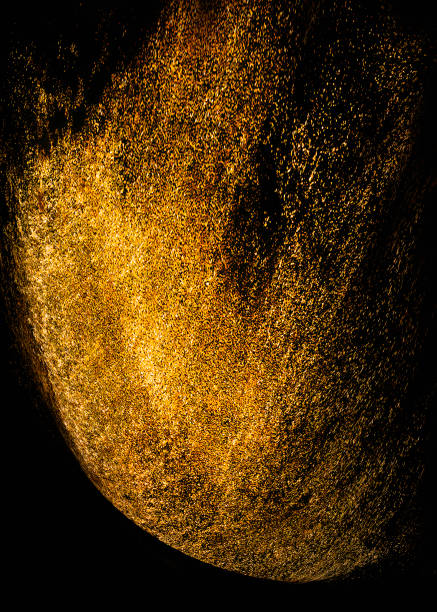 istock Golden sequins glisten with dust isolated on a black background. vertical abstract background with sparkling dust, space for text 1437883489