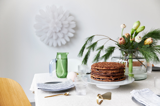 A gingerbread cake stands on a table decorated in a modern, Christmassy way