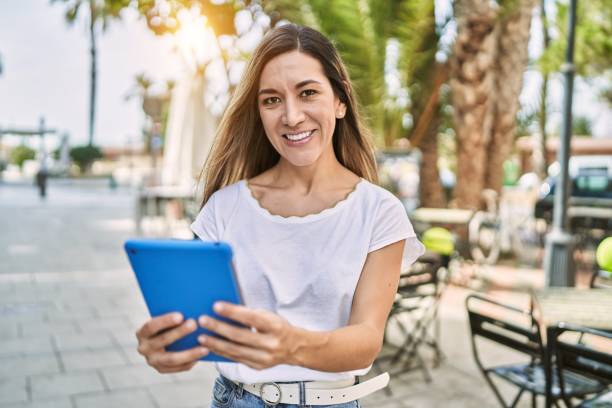 istock Young hispanic woman smiling confident using touchpad at street 1437883695