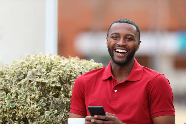 istock Happy black man holding phone looking at you 1437884723