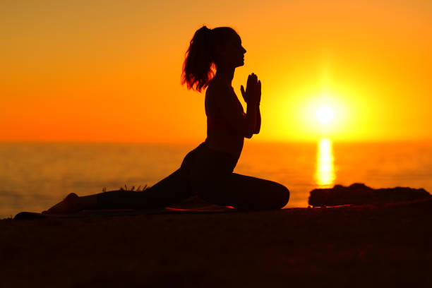 istock Female doing yoga at sunset on the beach 1437884760