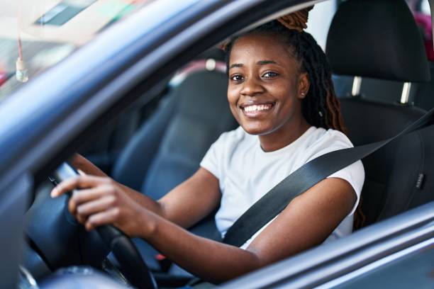 afroamerykanka uśmiechnięta pewnie jadąca samochodem na ulicy - people behavior smiling mode of transport zdjęcia i obrazy z banku zdjęć